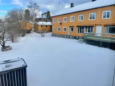 a snow covered yard in front of a building at Nye Heimen Overnatting in Namsos
