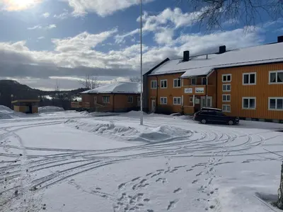 a snow covered parking lot in front of a building at Nye Heimen Overnatting in Namsos