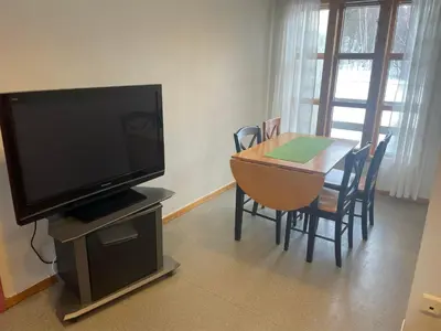 a living room with a television and a table with chairs at Nye Heimen Overnatting in Namsos