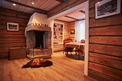 a living room with a fireplace and a dining table at Billingen Seterpensjonat in Skjåk