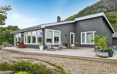 a house with a deck with a table and chairs at Gorgeous Home In Revsnes With Wifi in Refsnes