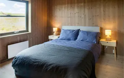 a bedroom with a bed with blue sheets and a window at 4 Bedroom Lovely Home In Østby in Østby