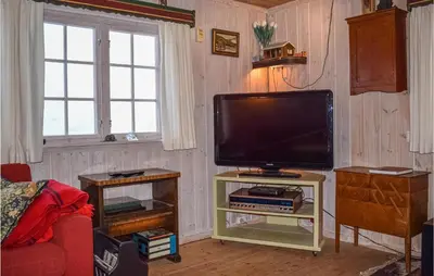 a living room with a flat screen tv on a stand at Cozy Home In Tuddal With Kitchen in Tuddal