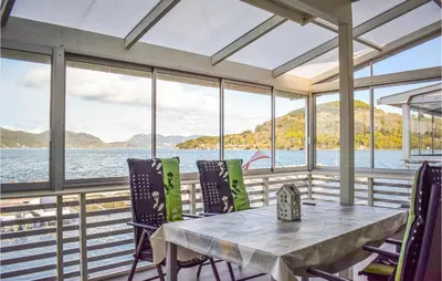 a table and chairs in a room with a view of the water at 4 Bedroom Lovely Home In Vikebygd in Vikebygd