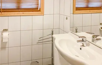 a white bathroom with a sink and a window at Beautiful Home In Sjusjoen in Sjusjøen