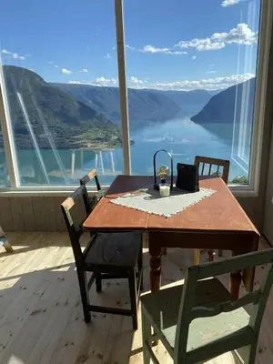 a table and chairs on a balcony with a view at Raaum Gard, hytte 2 in Hafslo