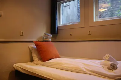 a bed with an orange pillow and towels on it at Dinbnb Apartments I Charming 3-Bedroom in the Heart of the City in Bergen