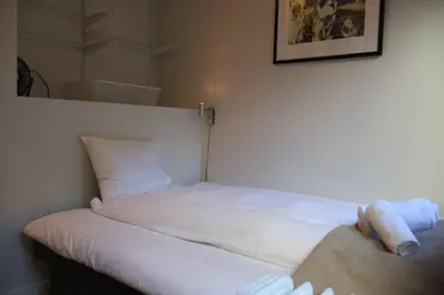 a bed in a room with white sheets and pillows at Dinbnb Apartments I Charming 3-Bedroom in the Heart of the City in Bergen