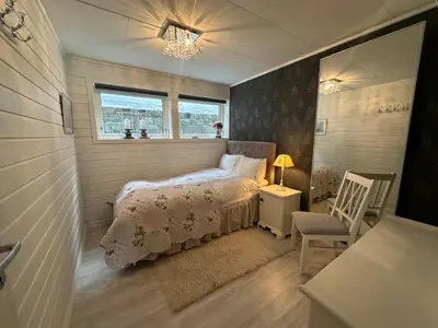 a small bedroom with a bed and a chair at Koselig leilighet i rolig boligfelt in Gol