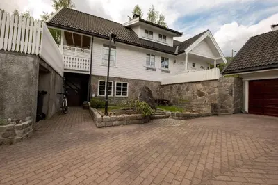 a large white house with a brick driveway at Koselig leilighet i rolig boligfelt in Gol