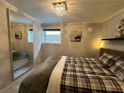 a bedroom with a large bed and a mirror at Koselig leilighet i rolig boligfelt in Gol
