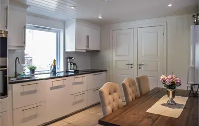 a kitchen with white cabinets and a wooden table with chairs at Stunning Home In Førde I Hordaland in Lier