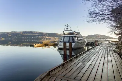 a boat is docked at a dock in the water at Villa Arboretet - Seaside villa with private pool & infrared sauna in the heart of Arboretet, Bergen in Bergen