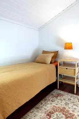 a bedroom with a bed and a nightstand and a table at Villa Arboretet - Seaside villa with private pool & infrared sauna in the heart of Arboretet, Bergen in Bergen