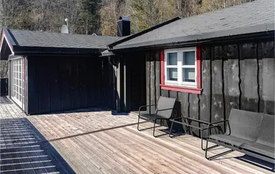 a black cabin with two chairs on a wooden deck at Cozy Home In Meisingset With Kitchen in Meisingset