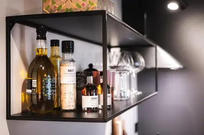 a shelf with alcohol bottles and glasses on it at Studio Leilighet, nyoppusset in Langevåg