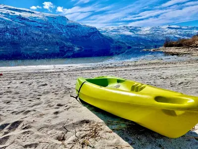 a yellow kayak sitting on a beach next to the water at Perlen på solheim I Hyen in Vereide