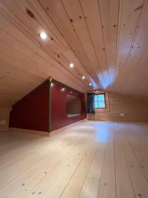 a large room with wooden floors and a red wall at Perlen på solheim I Hyen in Vereide
