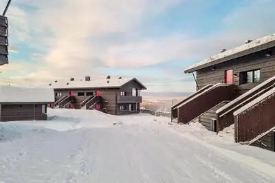 a snow covered road in front of two buildings at New ap The Nest in Hafjell ski in out and fast Wifi in Øyer