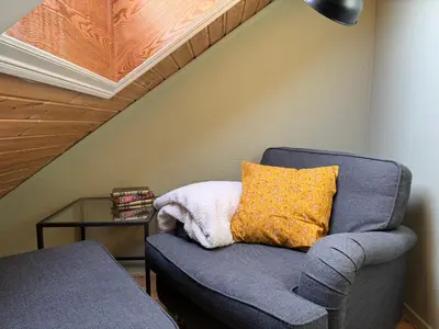 a blue chair with a yellow pillow and a table at Cozy backyard apartment in Trondheim