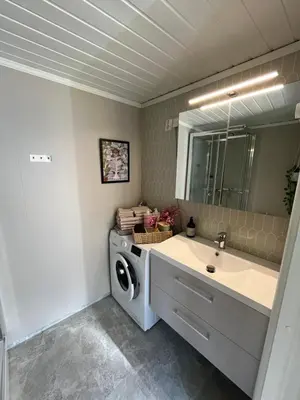 a bathroom with a washing machine and a sink at Cozy backyard apartment in Trondheim