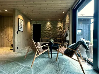 a living room with chairs and a table and a window at Brand new cabin on the sunny side of Gaustatoppen with a beautiful view in Tuddal