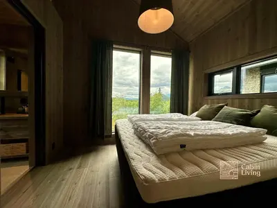 a bedroom with a bed and a large window at Brand new cabin on the sunny side of Gaustatoppen with a beautiful view in Tuddal