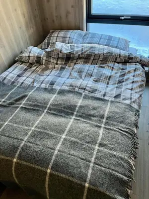 a bed in a room next to a window at Brand new cabin on the sunny side of Gaustatoppen with a beautiful view in Tuddal