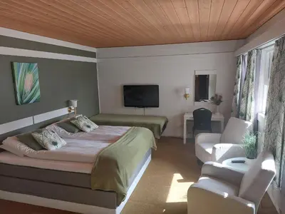 a bedroom with a bed and a couch and a tv at Øiseth Hotell AS in Rendalen