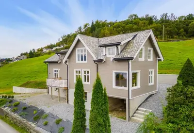 a house on a hill with trees in front of it at Hardangerfjord View - luxury fjord-side holiday home in Øystese