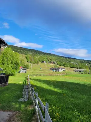a fence in a field with a hill in the background at Friends & Family Apartment at Hafjell Alpinlandsby/Øyer Center in Hafjell