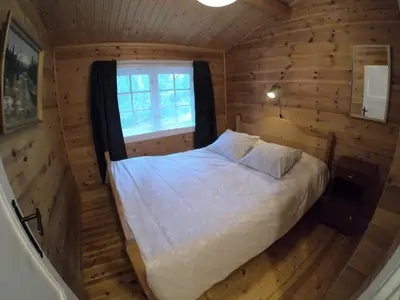 a bedroom with a bed in a log cabin at Gaulabua - cozy cabin by the river Gaula in Haltdalen