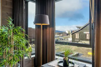 a room with a large window with plants and a lamp at Riddertunets glimt in Beitostøl