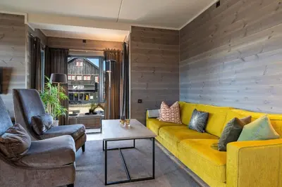 a living room with a yellow couch and two chairs at Riddertunets glimt in Beitostøl