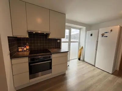 a kitchen with white cabinets and a refrigerator at 3 rooms apartment in Center in Ålesund