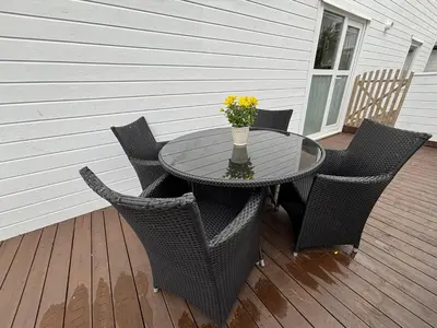 a table with chairs and a vase of flowers on a deck at 3 rooms apartment in Center in Ålesund