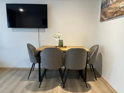 a dining room table with chairs and a television on a wall at 3 rooms apartment in Center in Ålesund