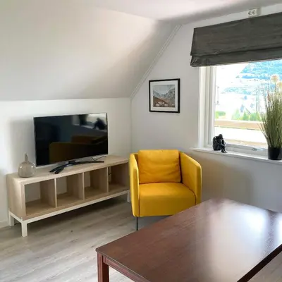 a living room with a yellow chair and a television at Store Ringheim Apartment - Villa Hjadlane in Vossevangen