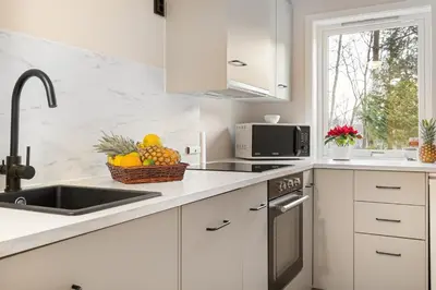 a white kitchen with a sink and a basket of fruit at Apartments Bergen free parking in Bergen