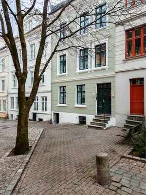 a building with a tree in front of it at Meltzers Apartments in Bergen