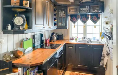a kitchen with black cabinets and a wooden counter top at 3 Bedroom Gorgeous Home In Molde in Molde