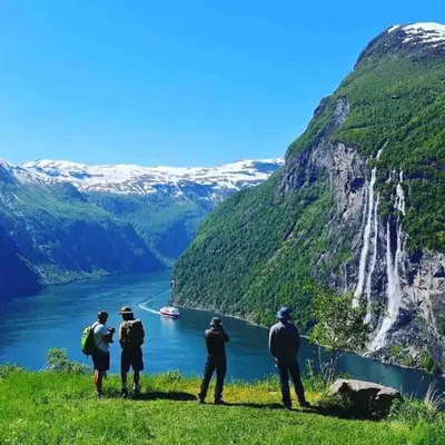 a group of people standing on a hill looking at a waterfall at Lovise Mountain Apartment in Stranda