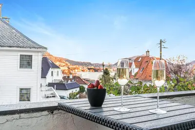 two wine glasses and a bowl of fruit on a table on a balcony at Big central apartment w/ a view and parking in Bergen