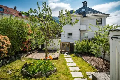 a garden in front of a white house at Big central apartment w/ a view and parking in Bergen