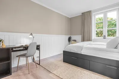 a bedroom with a bed and a desk with a desk at Big central apartment w/ a view and parking in Bergen