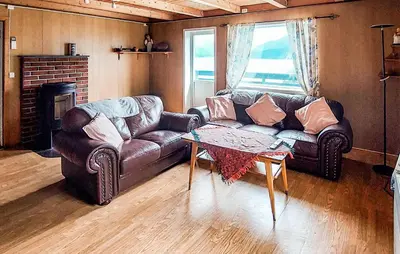 a living room with a leather couch and a table at Beautiful Home In Vallavik With Kitchen in Djønno