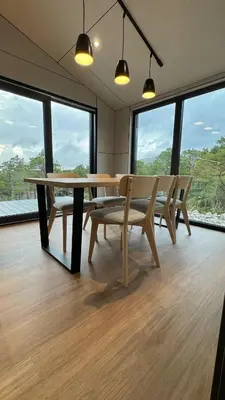 a dining room with a table and chairs and windows at Nothaugen AS in Nordheim