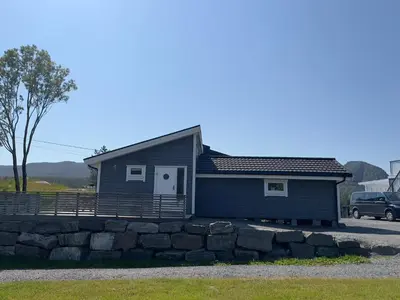 a small blue house with a stone wall at Nothaugen AS in Nordheim
