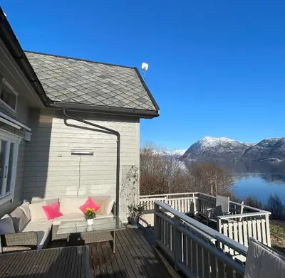 a porch with pink pillows and a couch on a deck at Secluded Holiday Home, With private beach in Ålesund