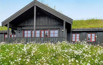 a black house with red windows and a field of flowers at Stunning Home In Gol With Sauna in Gol